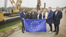 Gruppenfoto vor Arbeitsschiff mit Bagger/Kran