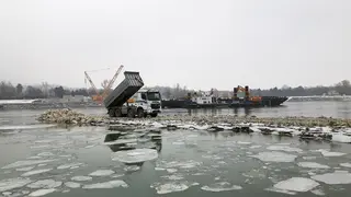 Schüttlaster auf Buhne, im Hintergrund Baggerschiff
