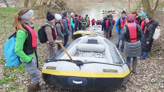 Personen an Flussufer rund um Schlauchboote
