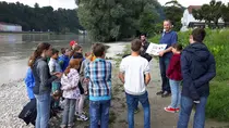 Experte erklärt einer Kindergruppe am Ufer verschiedene Naturschutzmaßnahmen