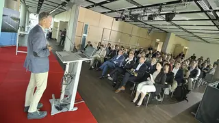 Presenter at the podium with audience in the background