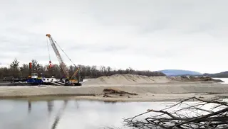 [Translate to English:] Bagger auf Ponton schüttet Kies auf der Donau