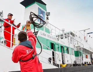 Matrose wirft Tau von Boot auf Schiff