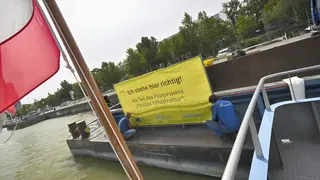 Arbeiter montieren gelbes Hinweisschild zum Einsatzzweck der Transportschute