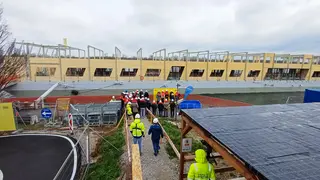 Büroschiff im Hintergrund, im Vordergrund Menschen auf dem Weg zum Schiff