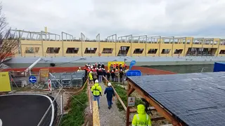 Büroschiff im Hintergrund, im Vordergrund Menschen auf dem Weg zum Schiff