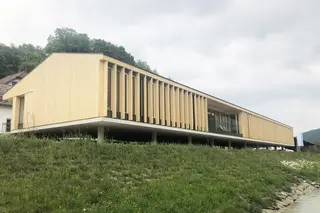 [Translate to English:] Totale des langgezogenen, ebenerdigen Holzbaus direktg am Donauufer