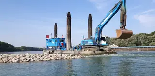 [Translate to English:] Bagger auf Schiff baggert an Buhne