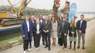Gruppenfoto vor Arbeitsschiff mit Bagger/Kran