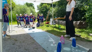 Kleine Kegelbahn mit Kindern, die Plastikflaschen umkegeln