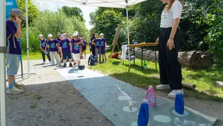 Kleine Kegelbahn mit Kindern, die Plastikflaschen umkegeln