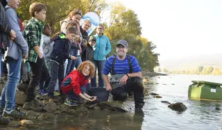 Kinder am Donauufer mit Jungfischen in der Hand